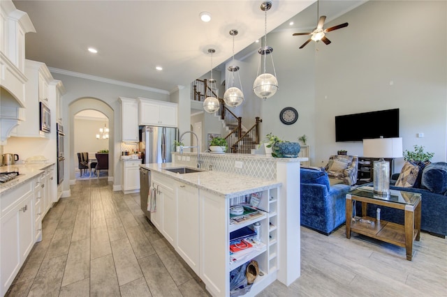 kitchen featuring white cabinetry, sink, stainless steel appliances, light hardwood / wood-style flooring, and a center island with sink