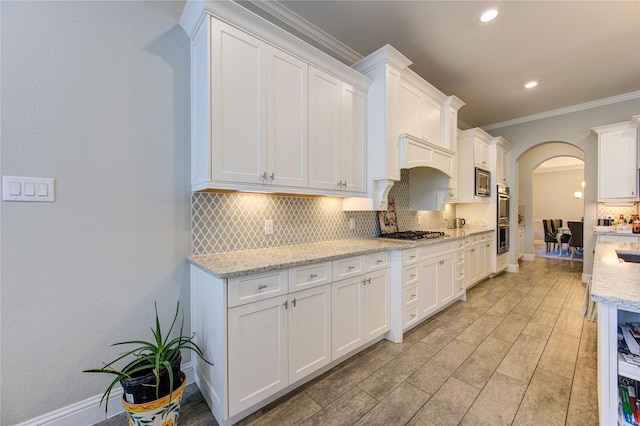 kitchen featuring light stone countertops, white cabinetry, ornamental molding, and appliances with stainless steel finishes