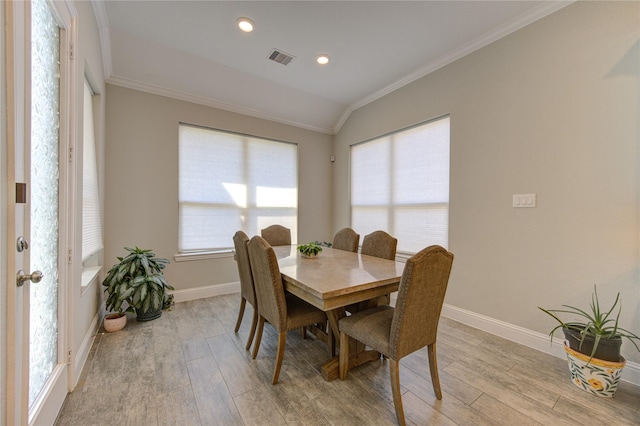 dining space featuring crown molding, light hardwood / wood-style floors, and vaulted ceiling