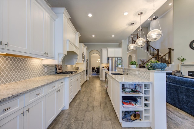 kitchen with light stone counters, white cabinetry, hanging light fixtures, and light hardwood / wood-style flooring