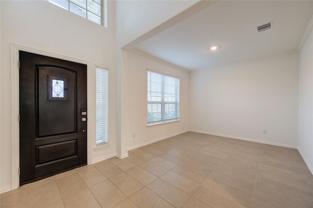 foyer with light tile patterned floors and crown molding