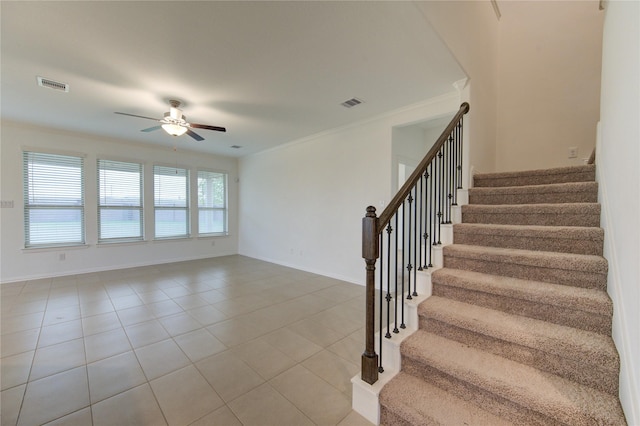 stairs featuring tile patterned flooring, ceiling fan, and crown molding