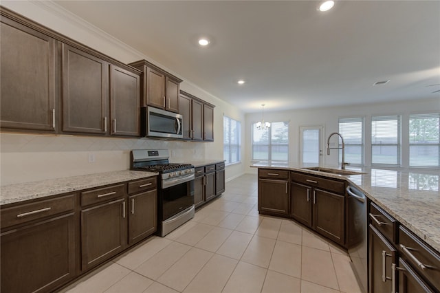 kitchen with sink, hanging light fixtures, light stone counters, a chandelier, and appliances with stainless steel finishes