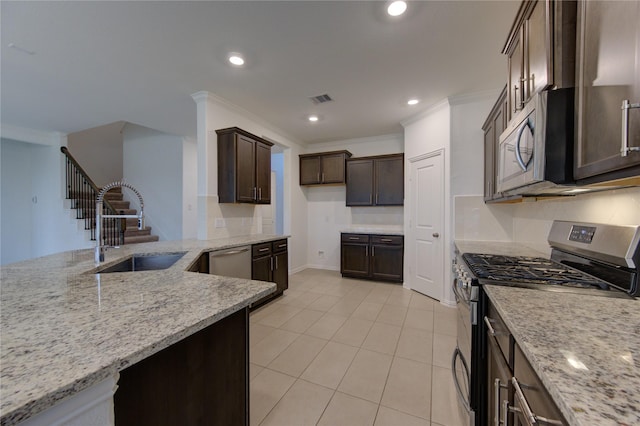 kitchen featuring light stone countertops, appliances with stainless steel finishes, ornamental molding, dark brown cabinets, and sink