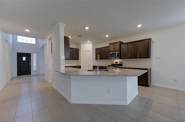 kitchen with light tile patterned floors, stainless steel appliances, light stone counters, and crown molding