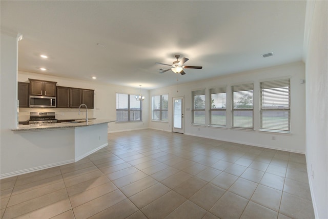 unfurnished living room featuring ceiling fan with notable chandelier, crown molding, light tile patterned floors, and sink