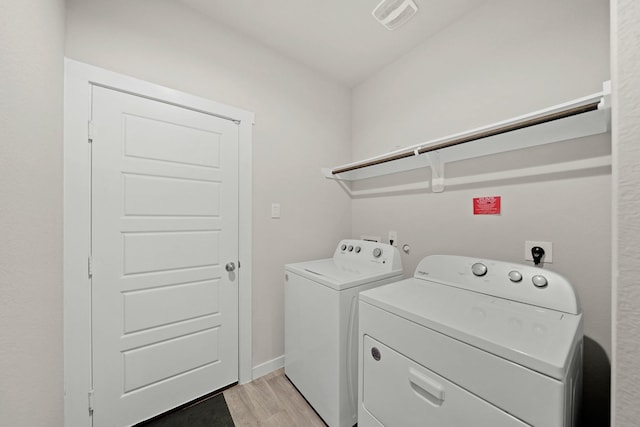 laundry room with washer and clothes dryer and light hardwood / wood-style flooring