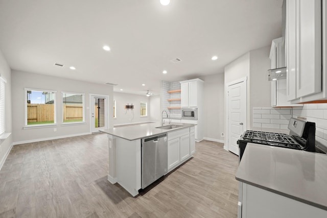 kitchen featuring appliances with stainless steel finishes, tasteful backsplash, a kitchen island with sink, sink, and white cabinetry