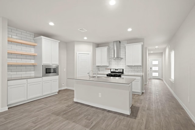 kitchen with white cabinetry, wall chimney exhaust hood, light hardwood / wood-style floors, and appliances with stainless steel finishes