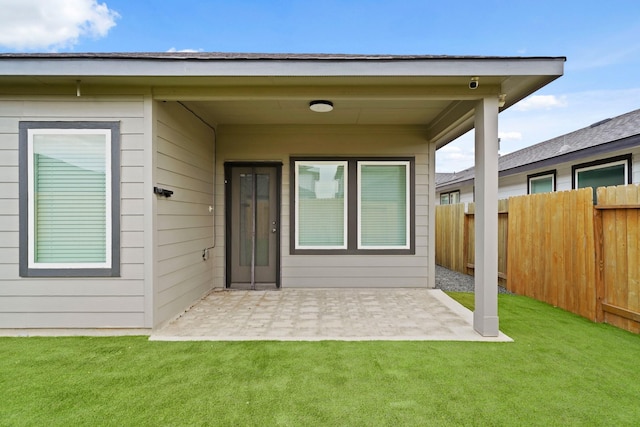 view of exterior entry with a lawn and a patio area