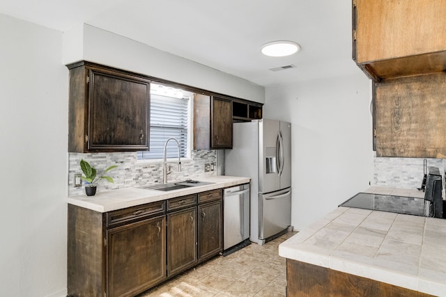 kitchen with backsplash, sink, stainless steel appliances, and dark brown cabinets