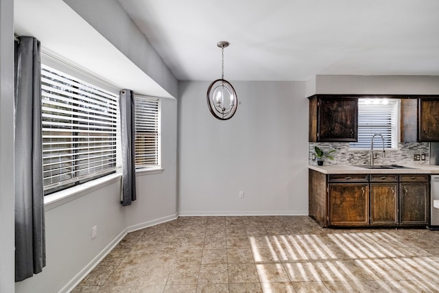 kitchen with decorative backsplash, dark brown cabinetry, sink, decorative light fixtures, and a chandelier