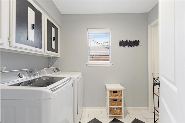 clothes washing area with washer and dryer, light tile patterned flooring, and cabinets