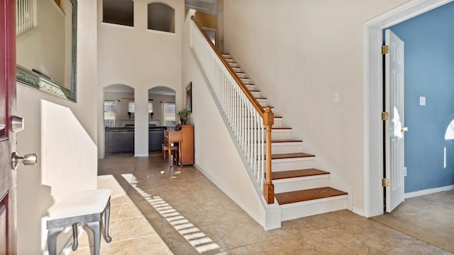 staircase featuring tile patterned flooring and a towering ceiling