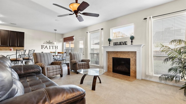 carpeted living room with a fireplace and ceiling fan