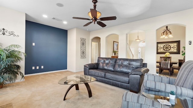 carpeted living room with ceiling fan with notable chandelier