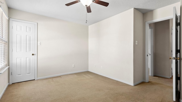 unfurnished room featuring a textured ceiling, ceiling fan, and light carpet