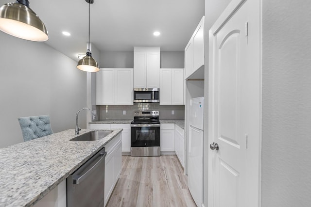 kitchen featuring white cabinets, sink, light hardwood / wood-style floors, light stone counters, and stainless steel appliances