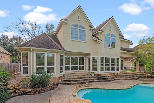 rear view of property with a fenced in pool