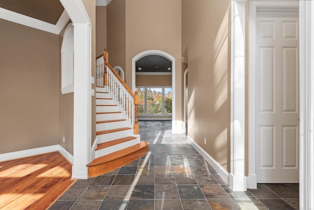 entryway with a high ceiling, dark hardwood / wood-style flooring, and crown molding