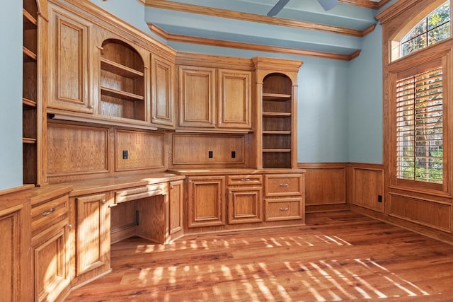 unfurnished office with built in features, light wood-type flooring, and crown molding