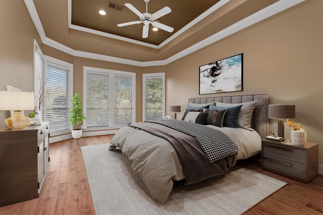 bedroom featuring a tray ceiling, ceiling fan, light hardwood / wood-style floors, and ornamental molding