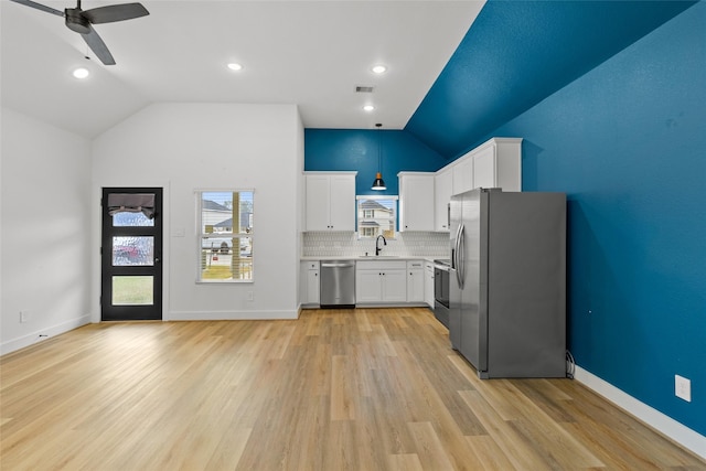 kitchen with lofted ceiling, sink, white cabinetry, stainless steel appliances, and decorative backsplash