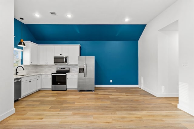 kitchen featuring sink, light hardwood / wood-style flooring, appliances with stainless steel finishes, white cabinetry, and hanging light fixtures