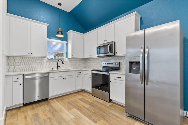 kitchen featuring sink, white cabinets, hanging light fixtures, stainless steel appliances, and light hardwood / wood-style flooring