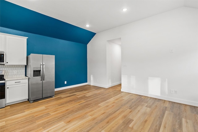 kitchen with backsplash, lofted ceiling, appliances with stainless steel finishes, and white cabinets