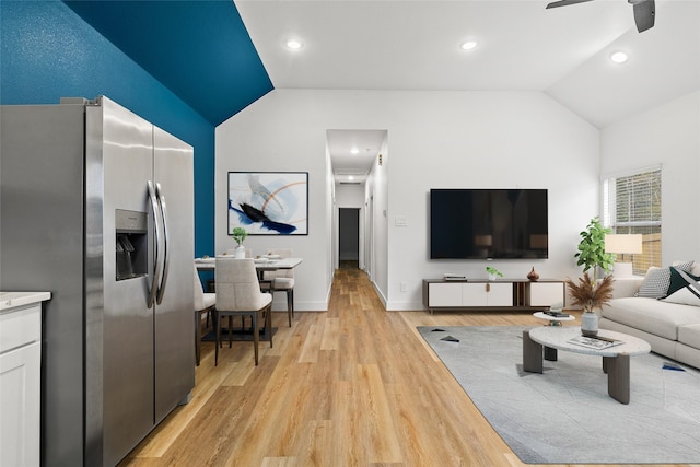 living room with light hardwood / wood-style flooring, vaulted ceiling, and ceiling fan