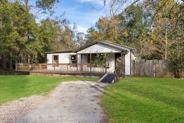 view of front of home featuring a wooden deck, covered porch, and a front yard