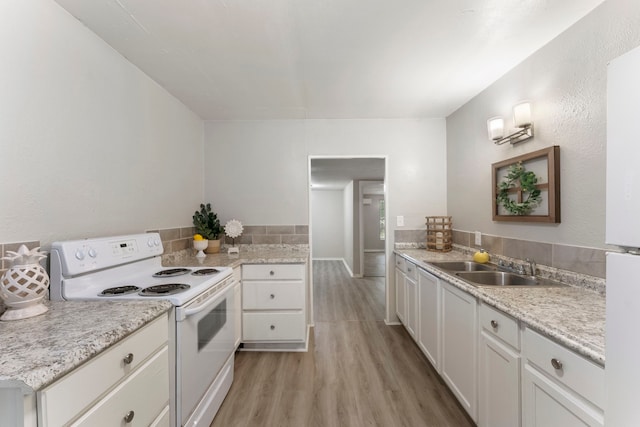 kitchen with sink, white range with electric stovetop, kitchen peninsula, light hardwood / wood-style floors, and white cabinets