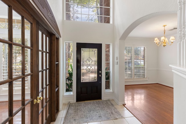 entrance foyer with light hardwood / wood-style flooring, a towering ceiling, and a notable chandelier