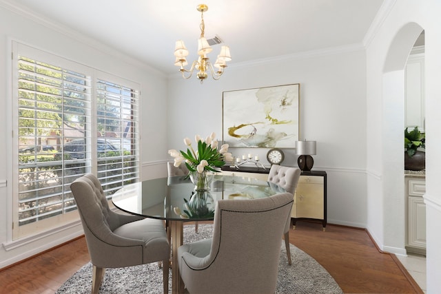 dining room with a notable chandelier, wood-type flooring, and crown molding