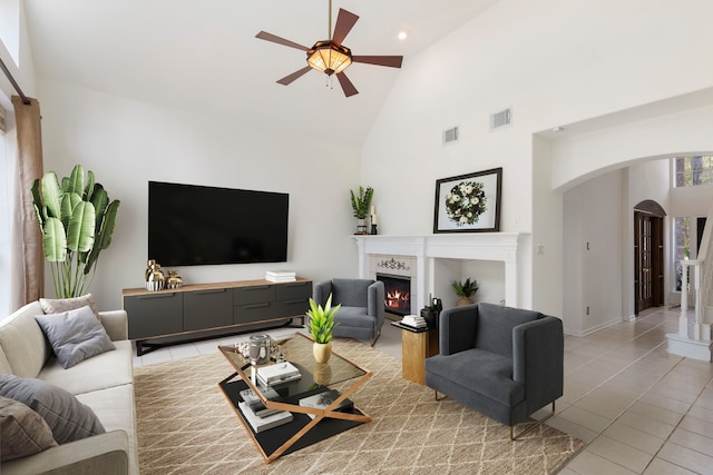 tiled living room with ceiling fan and high vaulted ceiling