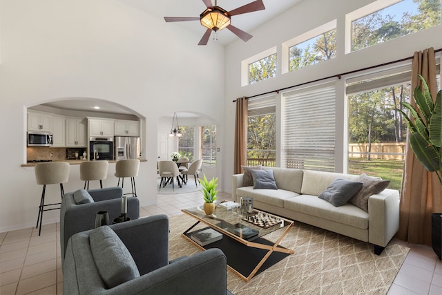 living room featuring light tile patterned floors, ceiling fan, and a high ceiling