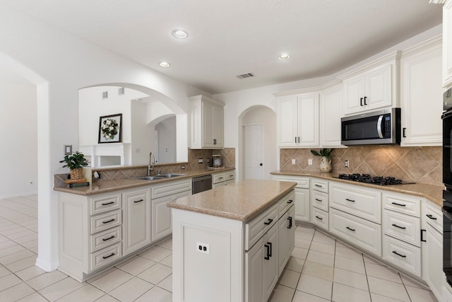 kitchen with white cabinets, sink, appliances with stainless steel finishes, tasteful backsplash, and a kitchen island