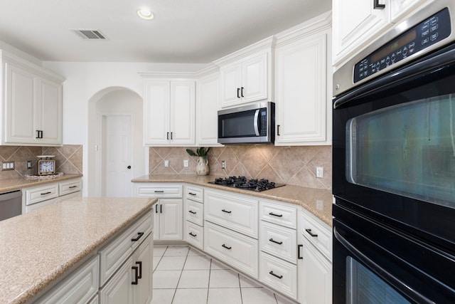 kitchen with white cabinets, decorative backsplash, and black appliances