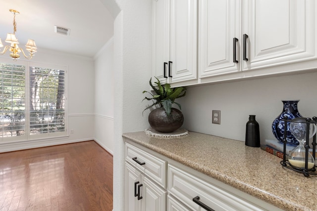 bar with white cabinets, crown molding, pendant lighting, a chandelier, and hardwood / wood-style floors