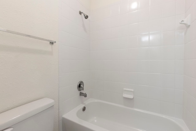 bathroom with tiled shower / bath combo and toilet