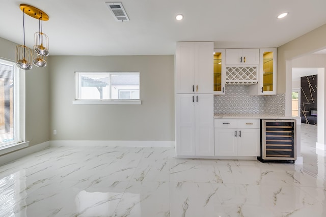 kitchen featuring white cabinets, a wealth of natural light, and beverage cooler