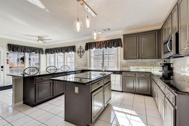 kitchen featuring light tile patterned floors, a center island, stainless steel appliances, and ornamental molding