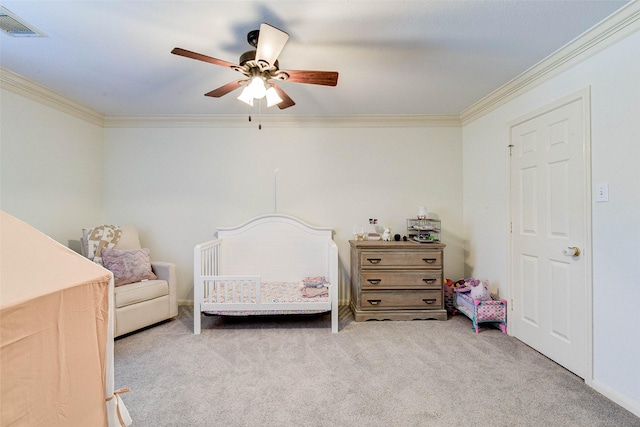 bedroom featuring ceiling fan, crown molding, light carpet, and a crib