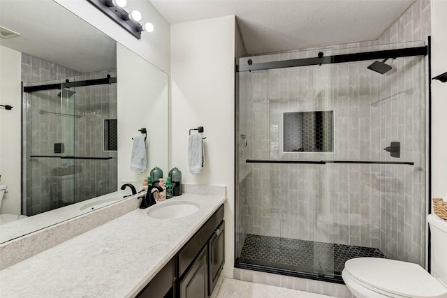 bathroom featuring vanity, toilet, a shower with shower door, and a textured ceiling