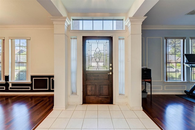 entrance foyer featuring light wood-type flooring, ornamental molding, and ornate columns