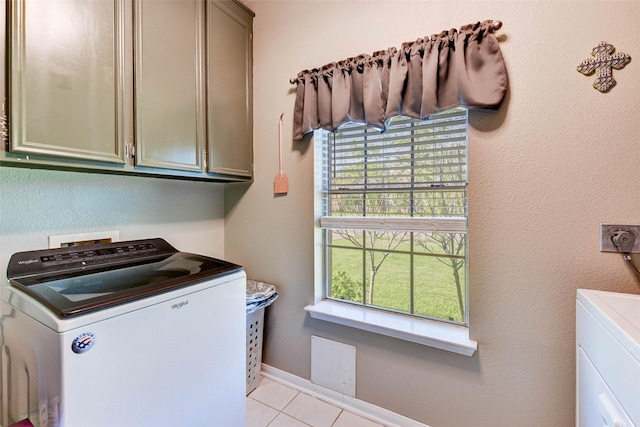 laundry area with washer and dryer, light tile patterned floors, and cabinets