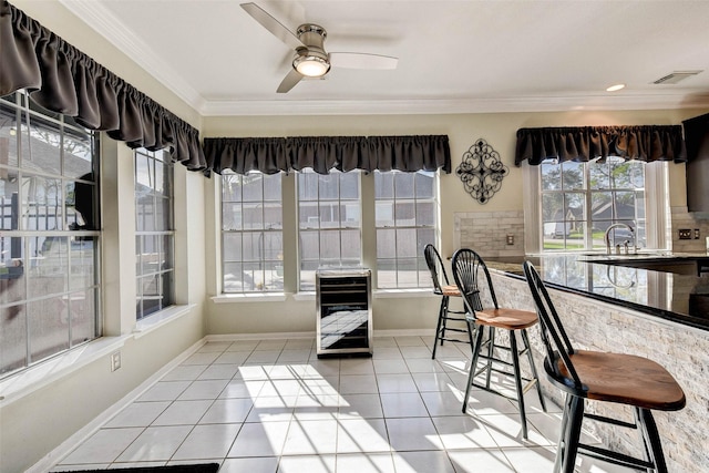 tiled dining space featuring ceiling fan, ornamental molding, sink, and wine cooler