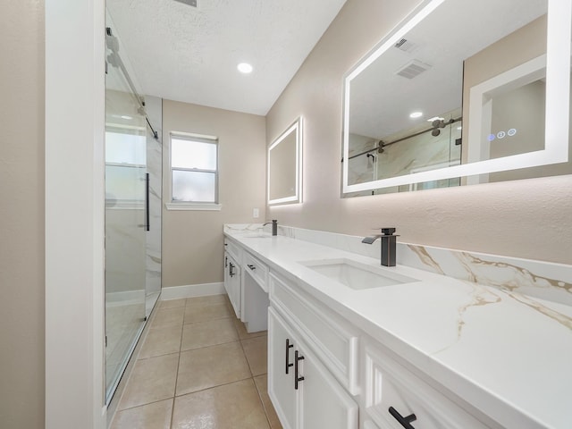 bathroom with tile patterned floors, vanity, a textured ceiling, and walk in shower