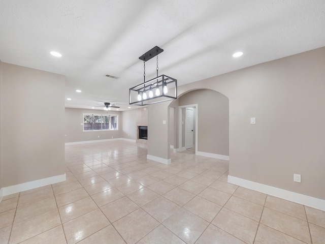 unfurnished living room featuring ceiling fan, light tile patterned flooring, and a textured ceiling